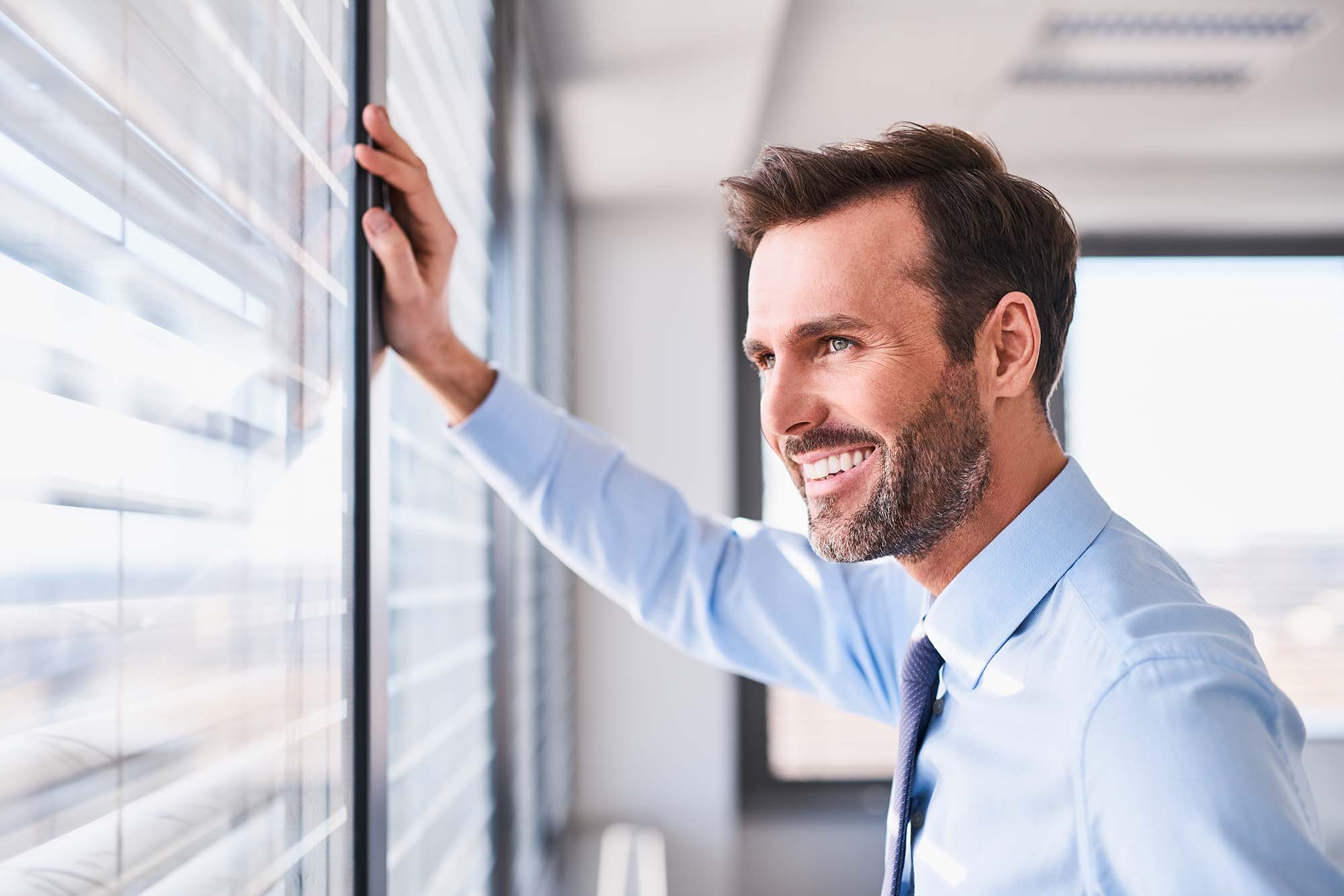 Senior man looking through window while smiling